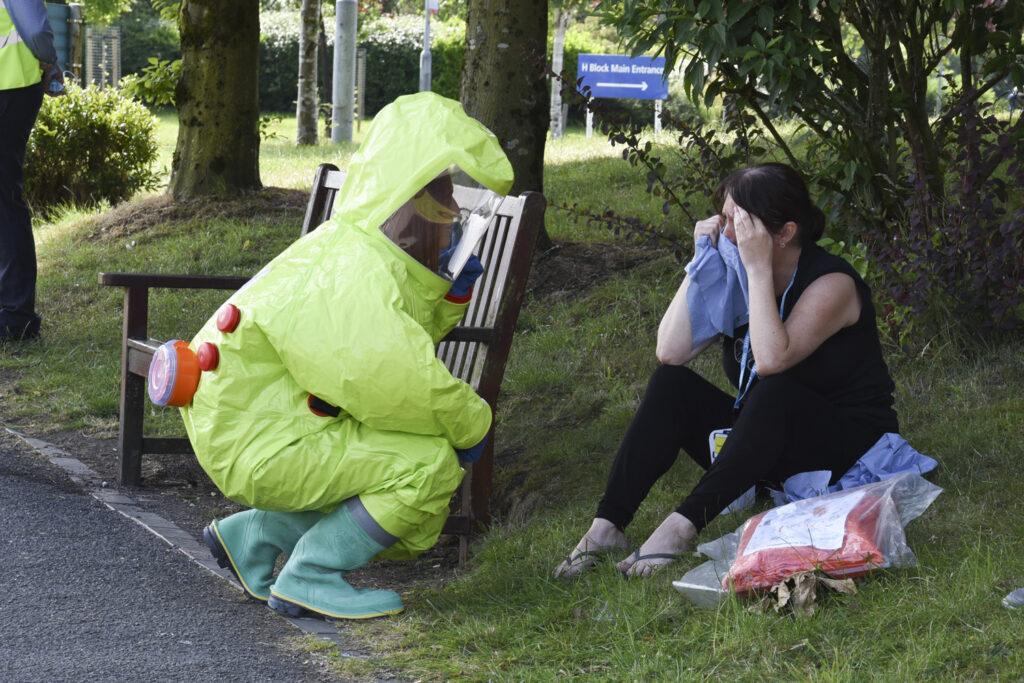 Nurse in chemical response PPE speaks to patient outside A&E