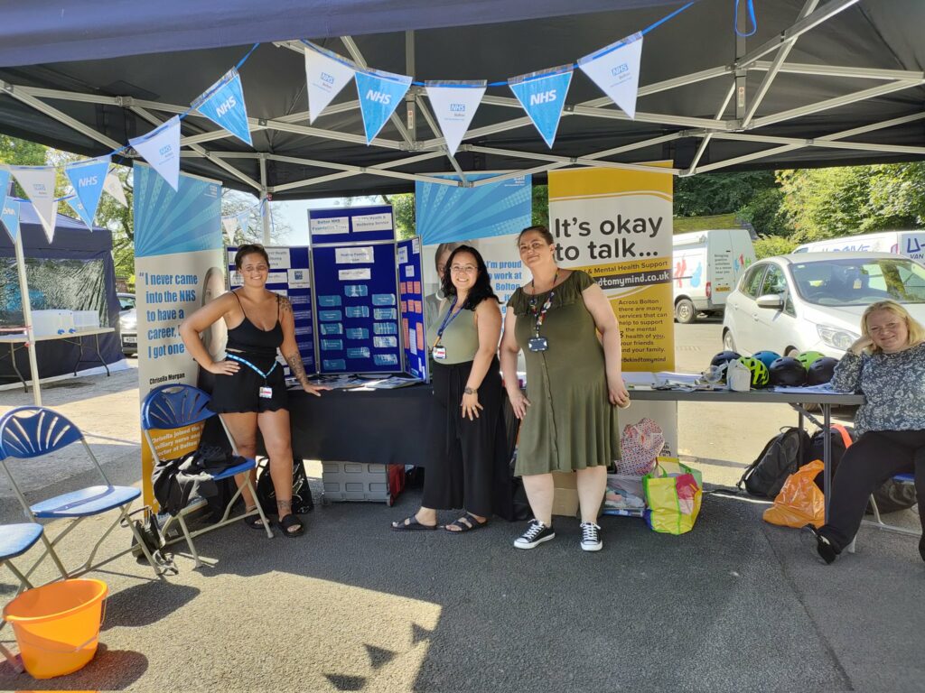 Three of the healthy families team stand in front of stand ready to help young people and their families