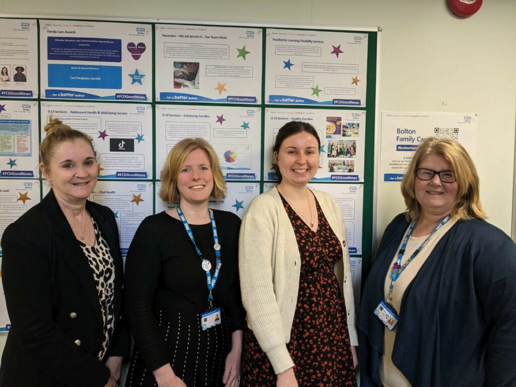 Tracy Iles, Audrey Abbott, Saskia McAdam and Bridget Thomas stand in front of a wall. All are smiling at the camera