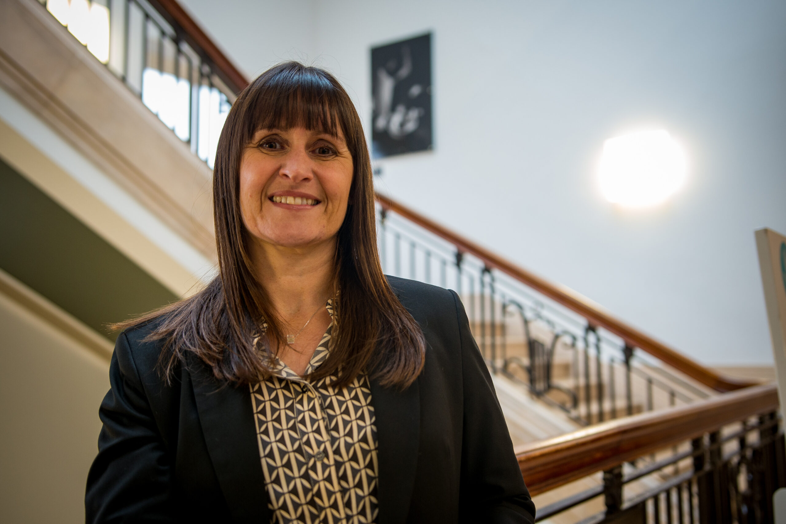 Rachel Tanner smiles at the camera next to a fancy staircase in Bolton town hall.