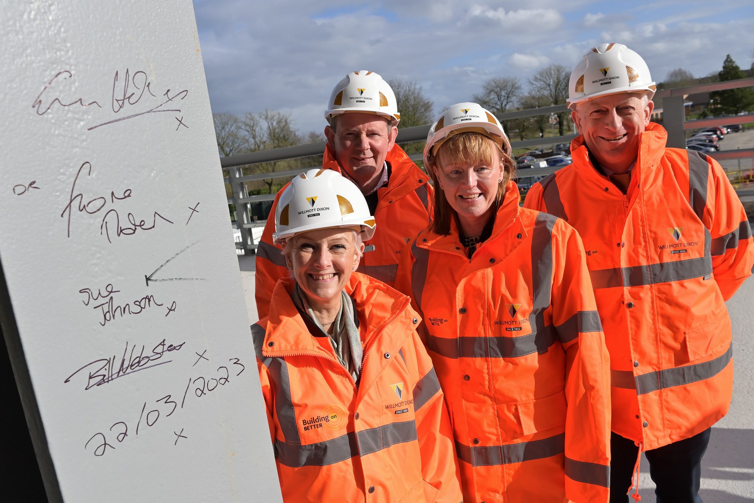 Two women and two men stand next to a grey steel