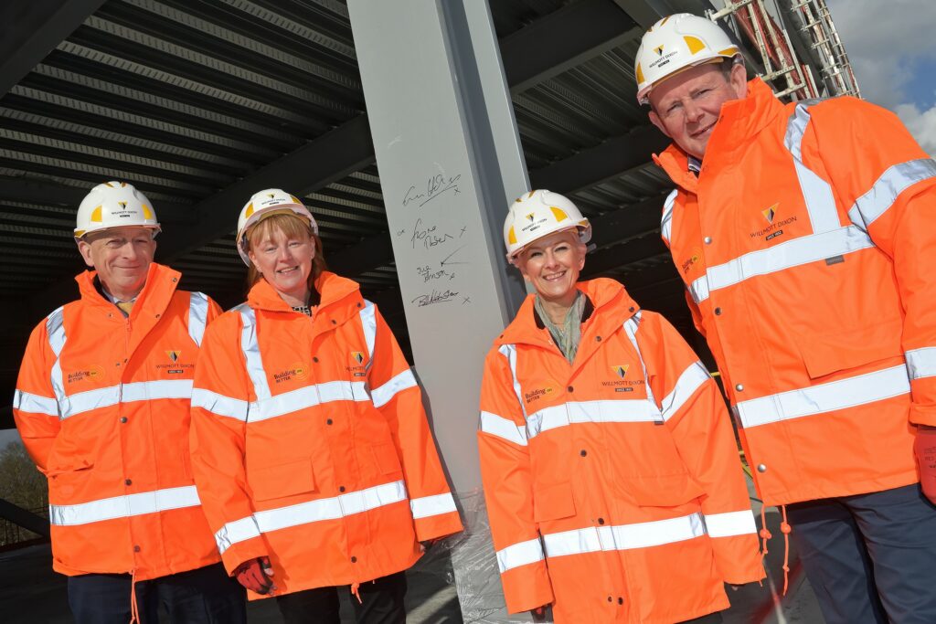 Two women and two men stand next to a grey steel