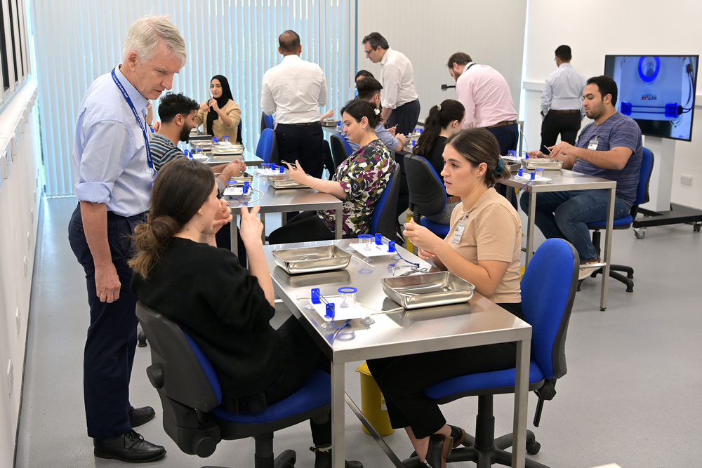 Nine young doctors learning surgical skills, accompanied by five course leaders. There are surgical instruments on the tables