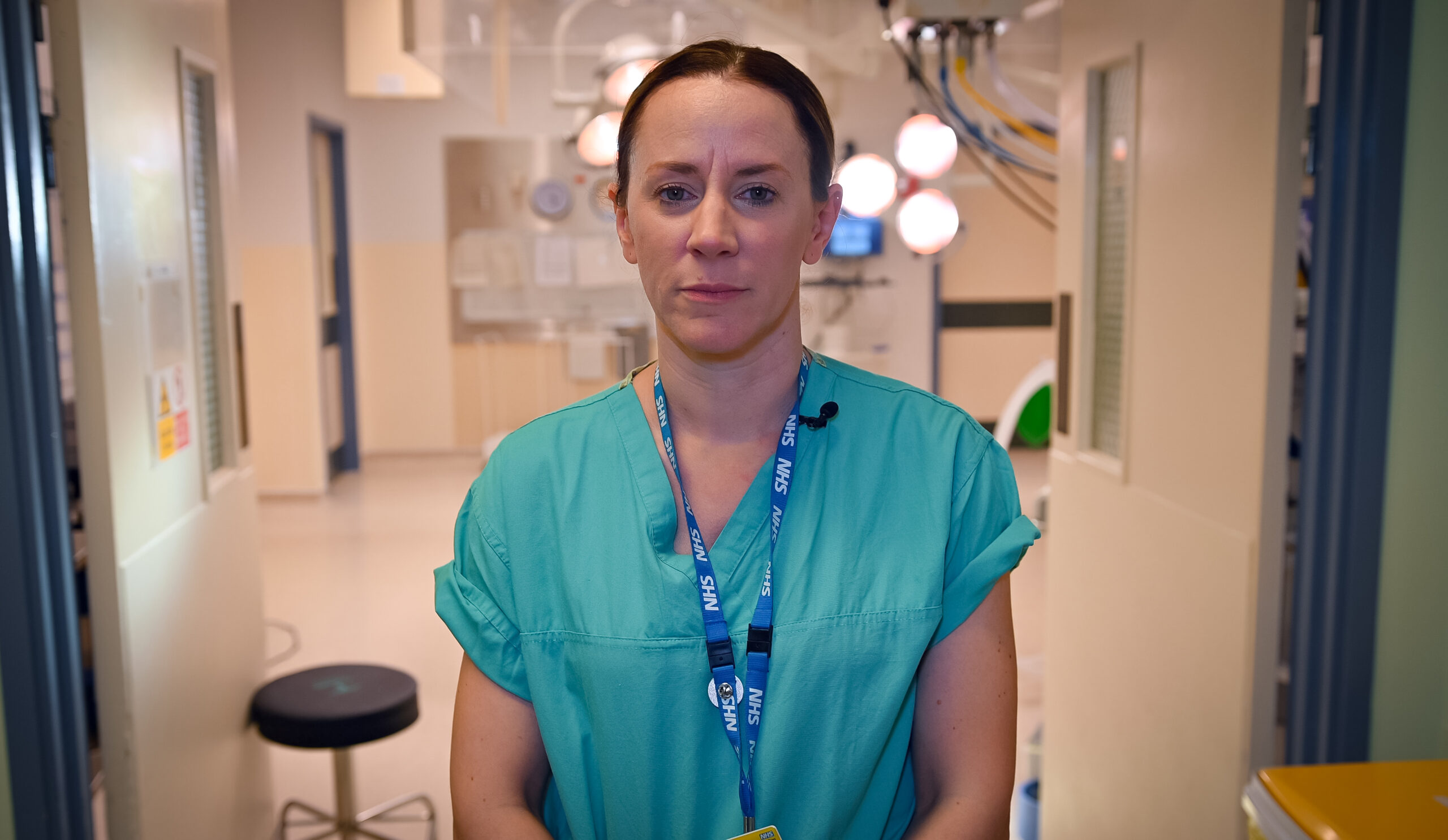 Associate Medical Director, Sophie Kimber Craig, stood in the entrance of a theatre room wearing her scrubs