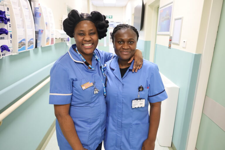 Oluchi and Kizzy smile for a picture in their blue uniform