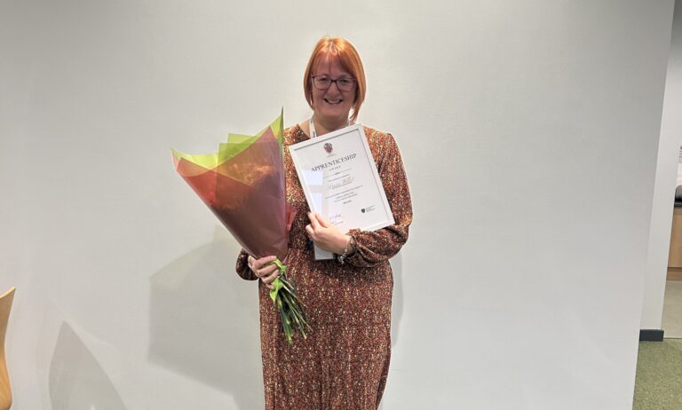 Leesa Willett with a bunch of flowers and an apprenticeship certificate