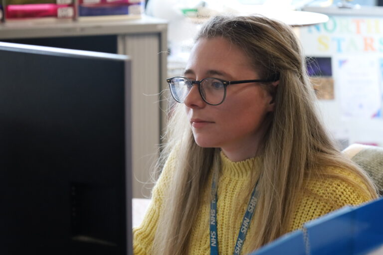 Admin colleague at Bolton NHS Foundation Trust sits at computer carrying out tasks