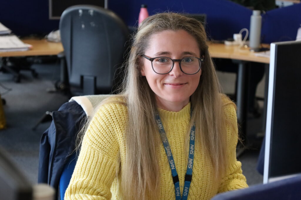 Olivia Poulsom smiles for a photo at her desk
