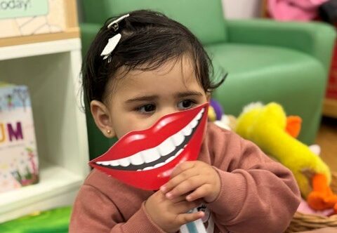 A young child uses a tooth prop at an activity group during National Smile Month