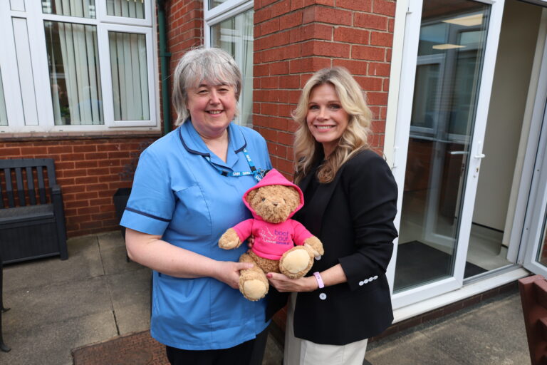 Debbie Dowie and Annette Trengrove pose for a picture with a Boot Out Breast Cancer teddy bear