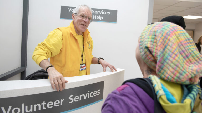 Bolton NHS FT volunteer has a conversation with two visitors