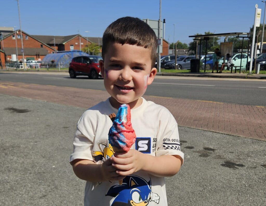 Young child smiles for a photo holding his free ice cream