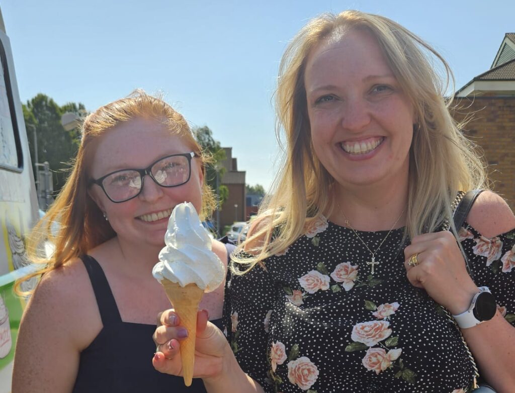 Two ladies smile for a photo holding their free ice cream