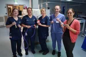 Hannah Spierson and Neonatal team smile for a picture holding equipment in Neonatal Unit