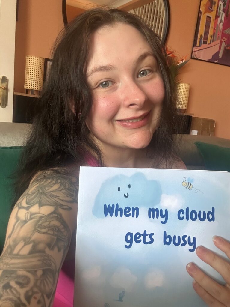 A selfie of Holly Mason holding her book 'When my cloud gets busy'